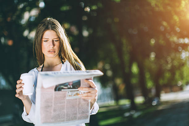 young woman reading the newspaper and drinking coffee